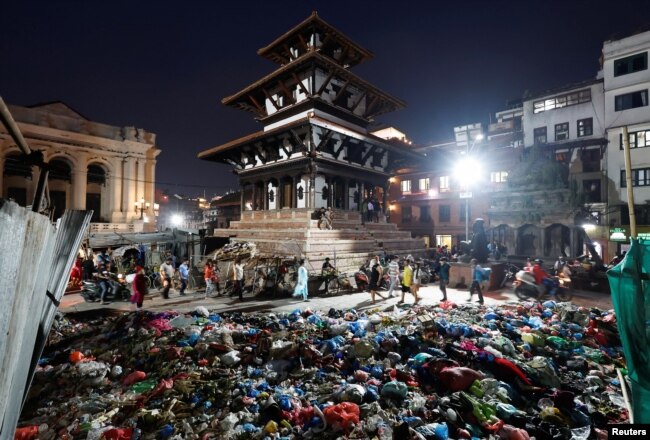 People walk near garbage dumped along the street in Bashantapur Durbar Square, a UNESCO world heritage site, as locals from a village near the dumping site protest against garbage being dumped in their area by blocking garbage trucks from reaching the dumping site, in Kathmandu, Nepal on June 7, 2022. (REUTERS/Navesh Chitrakar)