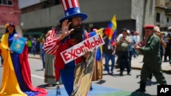 Un hombre vestido del Tío Sam sostiene un cartel de la petrolera estadounidense ExxonMobil, durante una marcha oficialista, en Caracas, Venezuela, el 26 de septiembre de 2023. (AP/Ariana Cubillos)