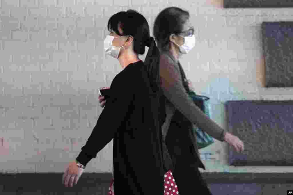 Women wearing protective masks to help curb the spread of the coronavirus walk Friday, Oct. 16, 2020, in Tokyo. The Japanese capital confirmed more than 180 new coronavirus cases on Friday. (AP Photo/Eugene Hoshiko)