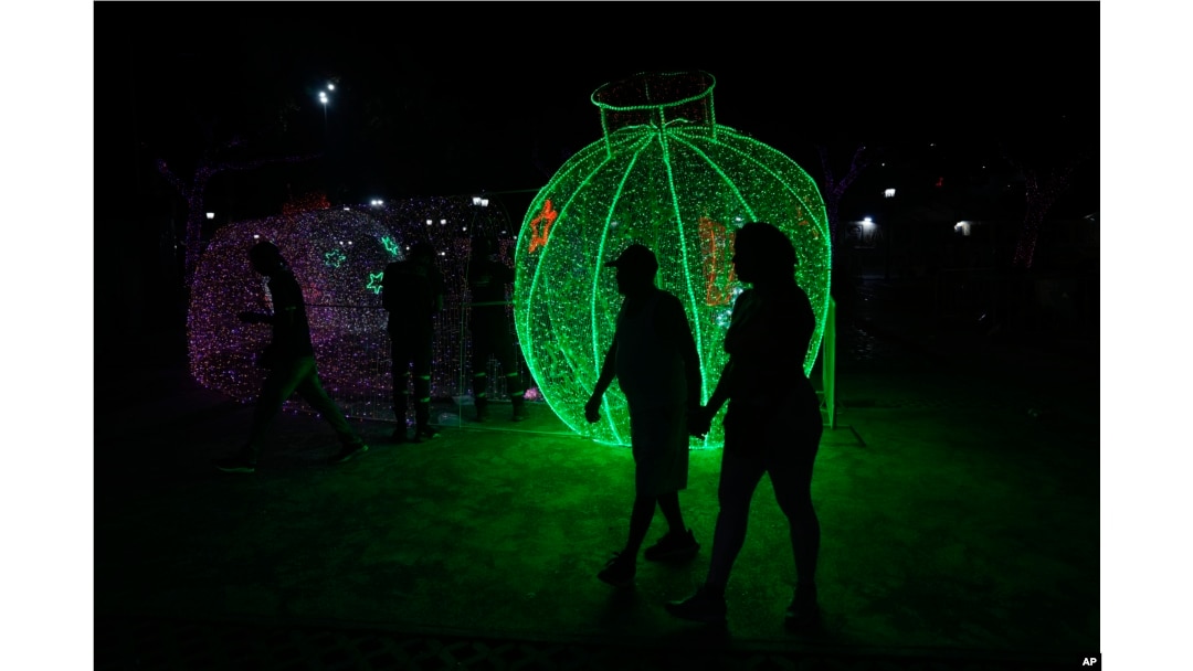 People walk past Christmas decorations in Caracas, Venezuela, Oct. 1, 2024. The decor went up months early due to a decree by President Nicolas Maduro.