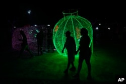 People walk past Christmas decorations in Caracas, Venezuela, Oct. 1, 2024. The decor went up months early due to a decree by President Nicolas Maduro.