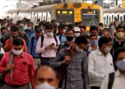 People wearing protective masks walk on a platform at the Chhatrapati Shivaji Terminus railway station, amidst the spread of the coronavirus disease, in Mumbai, India, March 16, 2021.