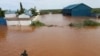 FILE—A man swims from a submerged church compound, after the River Tana broke its banks following heavy rains at Mororo, border of Tana River and Garissa counties, North Eastern Kenya, Sunday, April. 28, 2024.