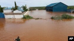 FILE—A man swims from a submerged church compound, after the River Tana broke its banks following heavy rains at Mororo, border of Tana River and Garissa counties, North Eastern Kenya, April. 28, 2024.