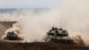 Israeli army tanks drive in an area near Israel's southern border with the Gaza Strip on October 6, 2024.