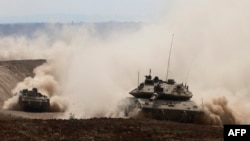 Israeli army tanks drive in an area near Israel's southern border with the Gaza Strip on October 6, 2024.