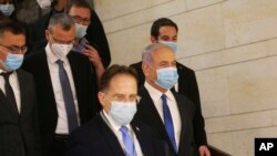 Israeli Prime Minister Benjamin Netanyahu, second right, wears a protective face mask, as he makes his way to attend the swearing in ceremony of his new government, at the Knesset, Israel's parliament, in Jerusalem, Sunday, May 17, 2020. 