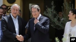 Cyprus' President Nicos Anasatsiades, right, and Turkish Cypriot leader Mustafa Akinci shake hands at Ledras palace crossing point in divided capital Nicosia in east Mediterranean island of Cyprus, June, 2, 2016.