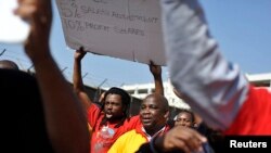 Striking members of the South African Transport and Allied Workers Union (SATAWU) hold placards outside Johannesburg's O.R. Tambo International Airport, Aug. 26, 2013.