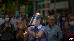 Una mujer aplaude a los manifestantes en una protesta de la derecha española contra el manejo de la pandemia que ha realizado el gobierno socialista.