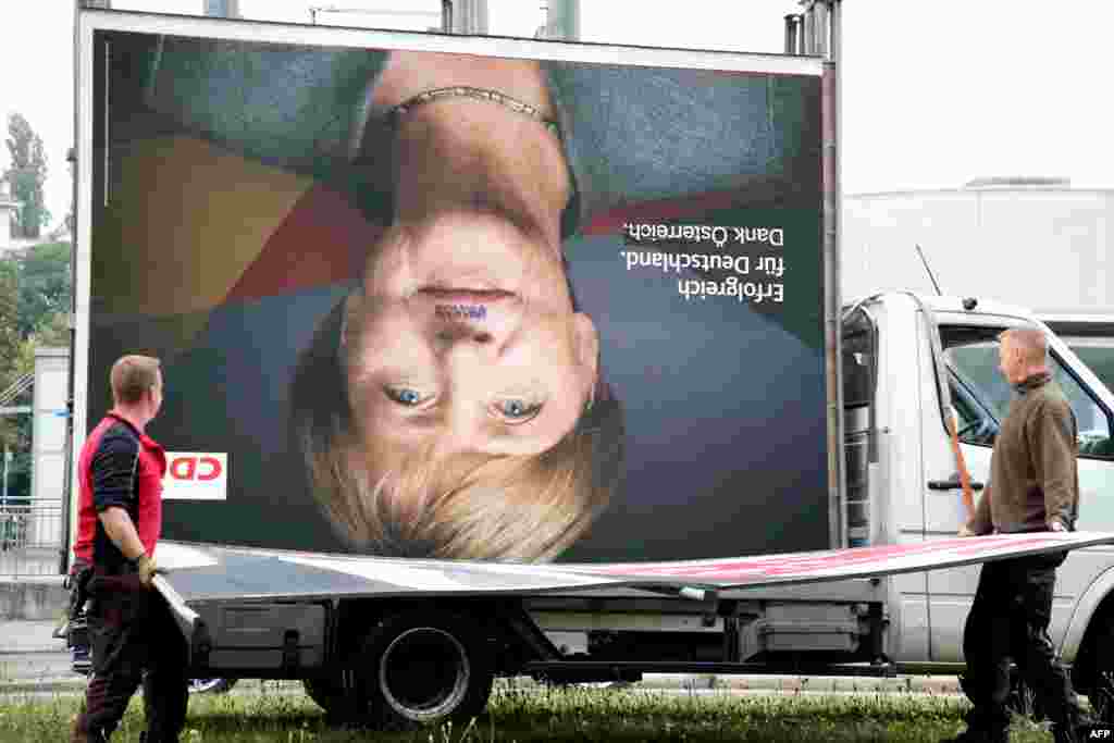 Employees of a billboard advertising company carry a disassembled election poster of Germany's Christian Democratic Union (CDU) party with the portrait of German Chancellor Angela Merkel in Berlin on September 25, 2017, one day after general elections.