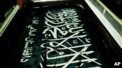 FILE - A worker hand prints Taliban flags in a small workshop in Kabul's Jawid market, Afghanistan, Sept. 12, 2021. 