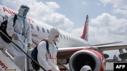 Passengers wearing full personal protective gears get off a plane at Jomo Kenyatta International Airport in Nairobi, Kenya, on January 19, 2021.