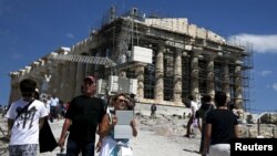 Para turis di depan kuil Parthenon di atas bukit Akropolis di Athena, Yunani (22/6). (Reuters/Alkis Konstantinidis)