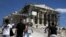 People are seen in front of the ancient Parthenon temple atop the Acropolis hill archaeological site in Athens, Greece, June 22, 2015. 