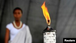 A girl stands in the background after escorting the Rwandan genocide flame, known as the 'Kwibuka' (Remembering) 20-years, at the Kicukiro Grounds as the country prepares to commemorate the 1994 Genocide in the Rwandan capital, April 5, 2014.