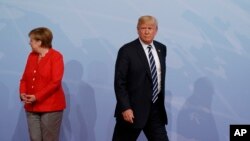 FILE - U.S. President Donald Trump walks off after being greeted by German Chancellor Angela Merkel after arriving at a G-20 Summit in Hamburg, Germany, July 7, 2017.