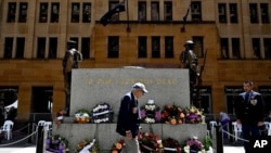 An elderly man wearing war medals walks past the cenotaph adorned with wreaths during a Remembrance Day Service in Sydney on Wednesday, Nov. 11, 2020. 