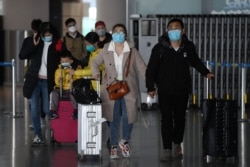 Passengers arrive from a domestic flight at Beijing Capital Airport, March 27, 2020. China will cut international flight routes and bar entry to returning foreigners based in the country to stem the spread of COVID-19, officials said.
