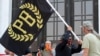 FILE - A protester carries a banner of the Proud Boys, a right-wing group, while other members start to unfurl a large U.S. flag in front of the Oregon State Capitol in Salem, Sept. 7, 2020. 