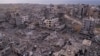 Palestinians walk through buildings that were destroyed by the Israeli air and ground offensive are seen at the Tel al-Hawa neighborhood in Gaza Strip, Jan. 28, 2025. 