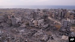 Palestinians walk through buildings that were destroyed by the Israeli air and ground offensive are seen at the Tel al-Hawa neighborhood in Gaza Strip, Jan. 28, 2025.