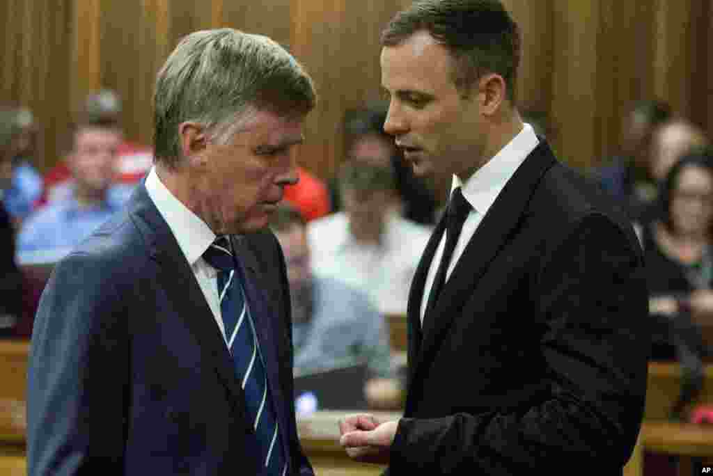 Oscar Pistorius talks with one of his defense lawyers on his arrival in court, Pretoria, Oct. 13, 2014. 