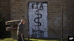 A man walks passes in front a wall painted with the anagram of the Basque separatist armed group ETA, reading '' ETA Together Always'' in Arbizu northern Spain, October 21, 2011.