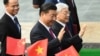 资料照：中共总书记、中国国家主席习近平与越共总书记阮富仲向举着中越国旗的欢迎人士挥手致意。(2017年11月12日)