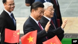 2017年11月12日，中國國家主席(中)和越共總書記阮富仲(右)在越南河內總統府舉行的歡迎儀式上揮手致意。（美聯社）