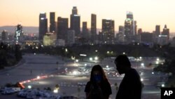 Pengunjung mengenakan masker saat mengamati lokasi vaksinasi COVID-19 di Stadion Dodger di Los Angeles, Jumat, 15 Januari 2021. (Foto AP / Marcio Jose Sanchez)
