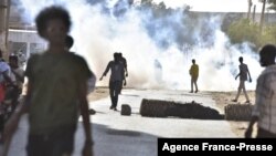 FILE - Protesters against the military coup in Sudan walk past fumes of tear gas fired by security forces during a demonstration in 'Street 60' in the east of capital Khartoum on Nov. 13, 2021.