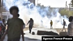 Des manifestants contre le coup d'État militaire au Soudan passent devant les fumées de gaz lacrymogènes tirées par les forces de sécurité lors d'une manifestation à Khartoum, le 13 novembre 2021. 