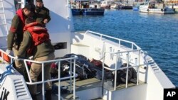 Turkish coast guard officers arrive with bodies of migrants that were drowned as they were trying to reach Greece, at a port near Izmir, Turkey, Jan. 21, 2016. 