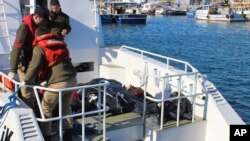 Turkish coast guard officers arrive with bodies of migrants that were drowned as they were trying to reach Greece, at a port near Izmir, Turkey, Jan. 21, 2016. 