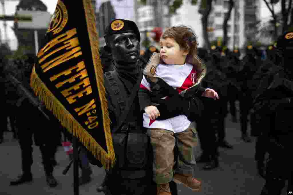 Intor Montoro Carba, a military special forces officer, holds Jeremy Bock for a photo, before the start of a military parade marking the country&#39;s Independence Day in Lima, Peru. Peru declared it&#39;s independence from Spain in 1821.