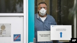 FILE - An employee with face mask and gloves waits for the next patient, behind the door of a coronavirus diagnostic center in Duesseldorf, Germany, March 2, 2020.
