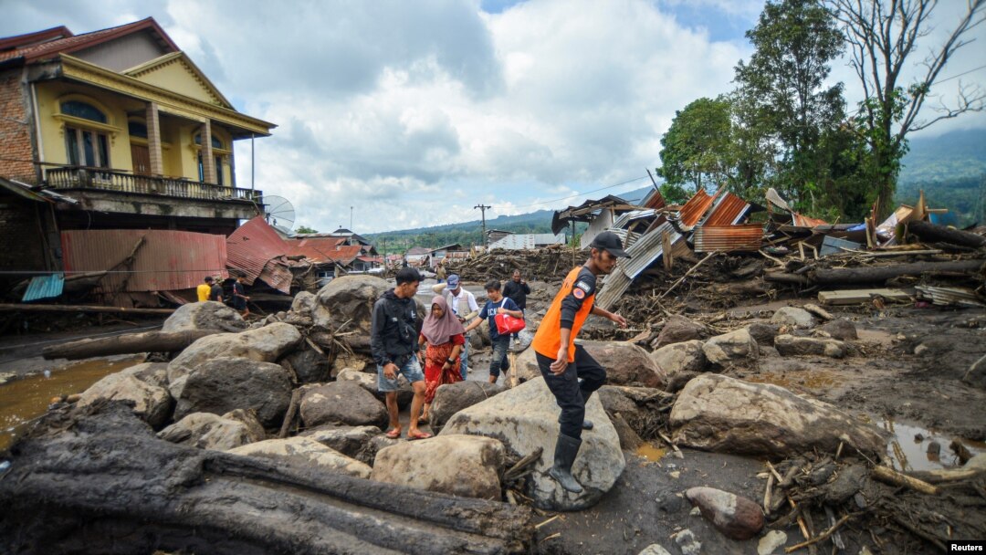 Warga berjalan di kawasan terdampak hujan lebat yang membawa banjir bandang dan tanah longsor saat mereka mengungsi di Agam, provinsi Sumatera Barat, 12 Mei 2024. (Antara Foto/Iggo El Fitra/via REUTERS)