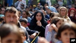 FILE - Migrants, mostly Syrians, listen to an Arabic speaker talk to them about their future as they rest in a stadium while waiting to cross to Europe near Turkey’s western border with Greece and Bulgaria, in Edirne, Turkey, Sept. 23, 2015.