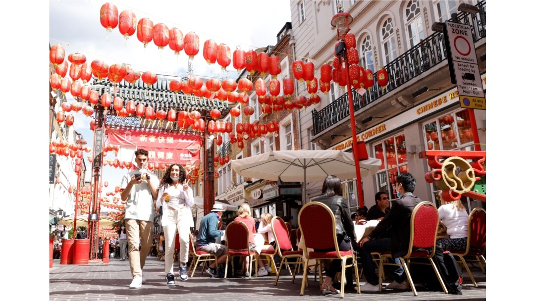 People walk past diners on the street in Chinatown, on the opening day of 'Eat Out to Help Out' scheme, amid the coronavirus disease (COVID-19) outbreak, in London, Britain, Aug. 3, 2020.