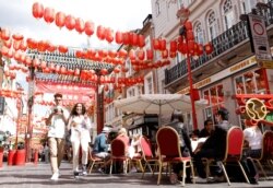 People walk past diners on the street in Chinatown, on the opening day of 'Eat Out to Help Out' scheme, amid the coronavirus disease (COVID-19) outbreak, in London, Britain, Aug. 3, 2020.