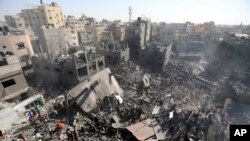 FILE - Palestinians inspect the rubble of destroyed buildings following Israeli airstrikes on the town of Khan Younis, southern Gaza Strip, October 26, 2023.