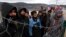 Migrants watch Bosnian soldiers put up tents at the Lipa camp outside Bihac, Bosnia, Jan. 1, 2021. Hundreds of migrants have been stuck in a burned-out camp in the northwest of the country in winter weather and with no facilities.