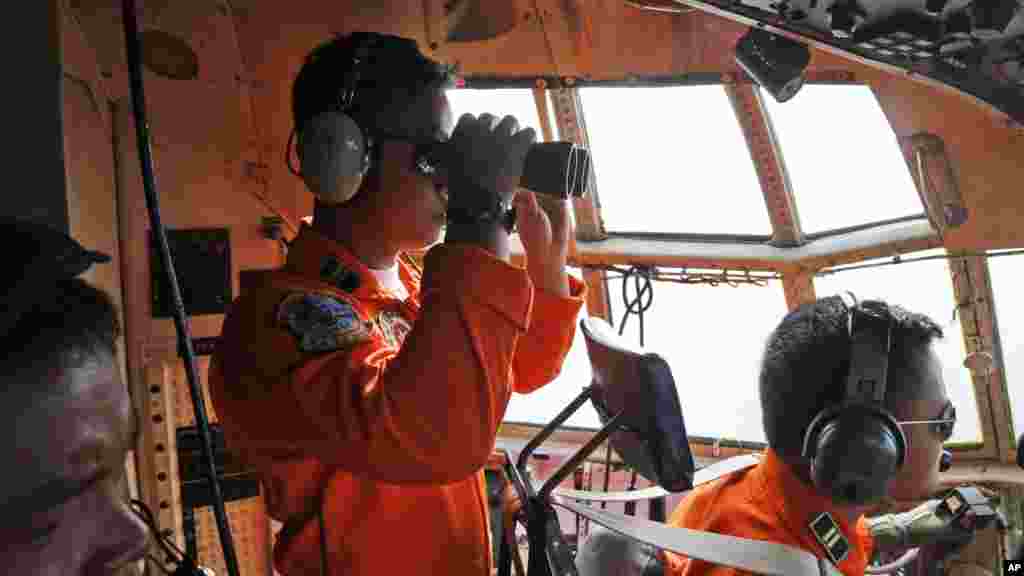 L&#39;équipage de la force aérienne indonésienne dans l&#39;avion Air Force C-130 du 31ème Air Escadro recours des jumelles pour scruter l&#39;horizon pendant une opération de recherche de l&#39;avion d&#39;AirAsie disparu sur les eaux du détroit de Karimata en Indonésie, le 29 décembre 2014.