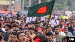 A student carrying the Bangladeshi flag takes part in a march as demonstrators demand justice for victims arrested and killed in the recent nationwide protests against job quotas, in Dhaka on Aug. 3, 2024.