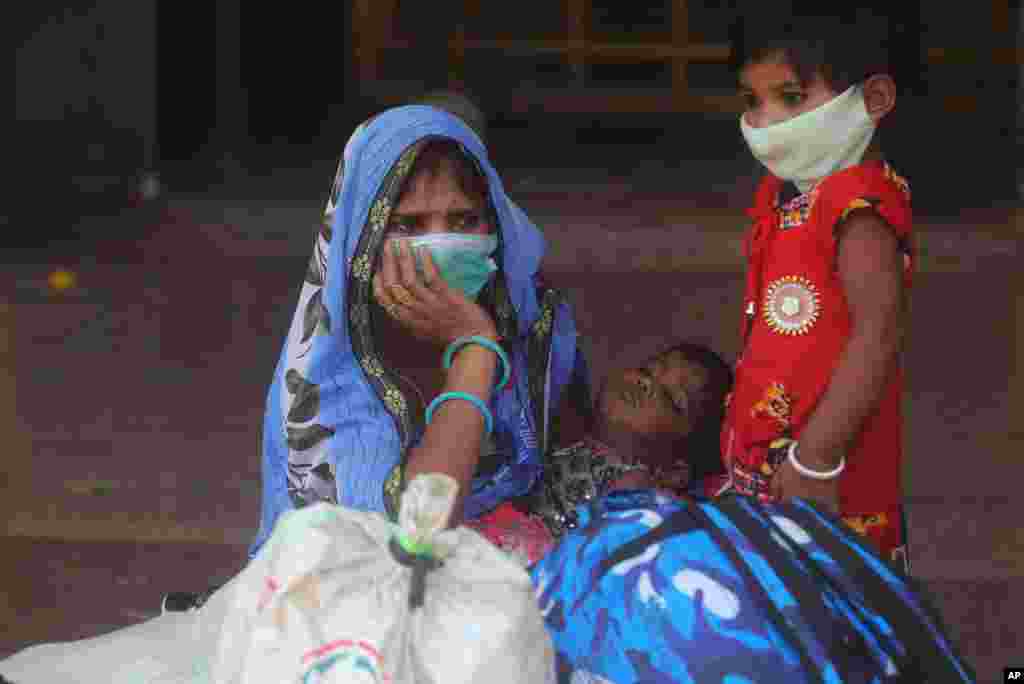 A woman and her children wait for a train at Lokmanya Tilak Terminus in Mumbai, India. India hits another new peak with 115,736 coronavirus cases reported in the past 24 hours.