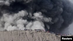 Warga berdiri di pinggir kawah sambil melihat letusan Gunung Bromo, di Probolinggo, 12 Juli 2016. 