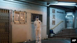 A person wearing a protective suit waits near a block's entrance at the Cheung Hong Estate, a public housing estate, during evacuation of residents in Hong Kong, Feb. 11, 2020. 