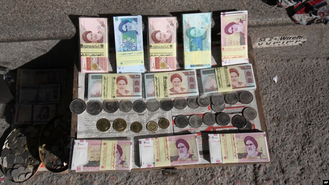 Iranian banknotes and foreign coins are displayed by a vendor on a Ferdowsi Street sidewalk in Tehran, Jan. 23, 2013.