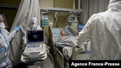 FILE - Medical workers wearing a personal protective equipment PPE tend to a patient infected with the Covid-19 at the intensive care unit of the Mariinsky Hospital in Saint Petersburg, Russia, July 7, 2021.